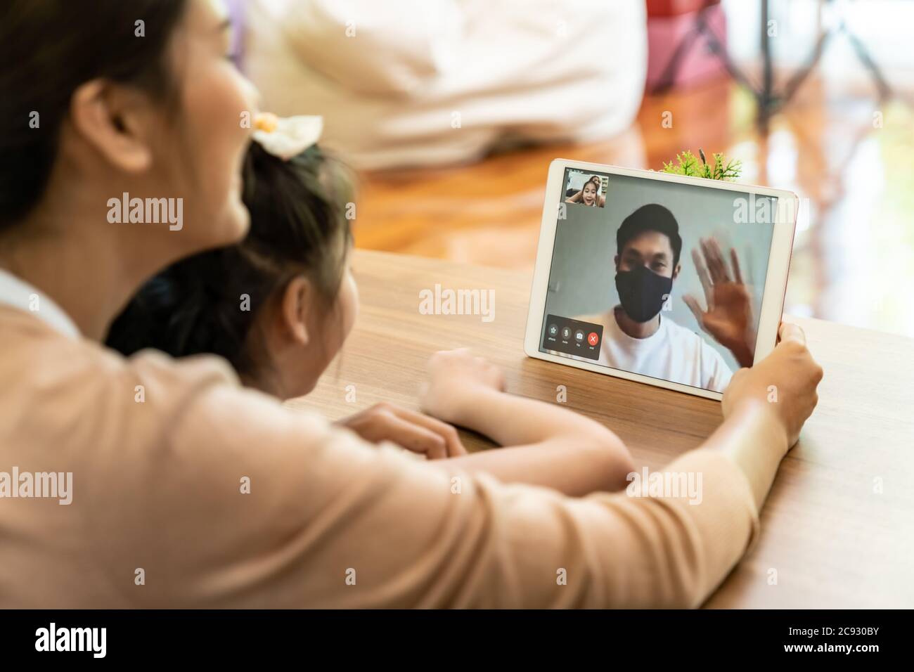 Quarantine father video conference call with his family of mom and daughter while stay in state quaratine. Technology and family reunion new normal wh Stock Photo