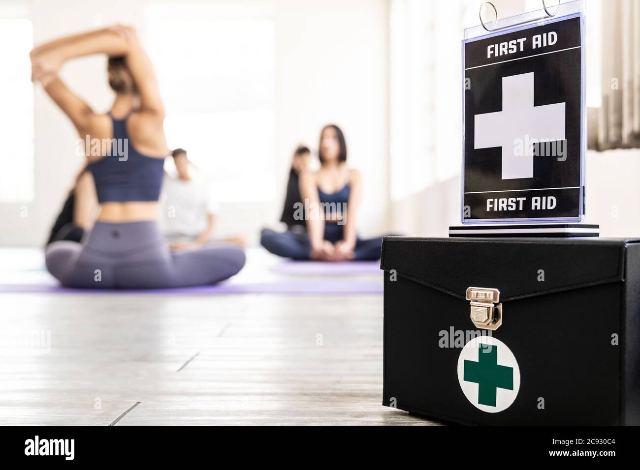 First aid box with its signage for safety in fitness gym with background of yoga class students and trainer. Healthy lifestyle and safety first sport Stock Photo