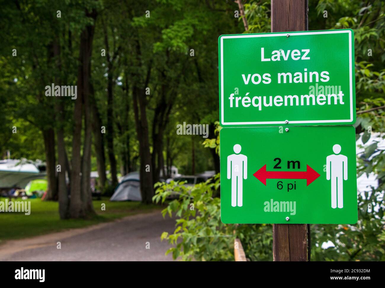 July 26, 2020 - Roxton Falls, Qc, Canada: Social distancing and 'Wash your hands' in French Road Signs on a campground, COVID-19 Coronavirus Pandemic Stock Photo