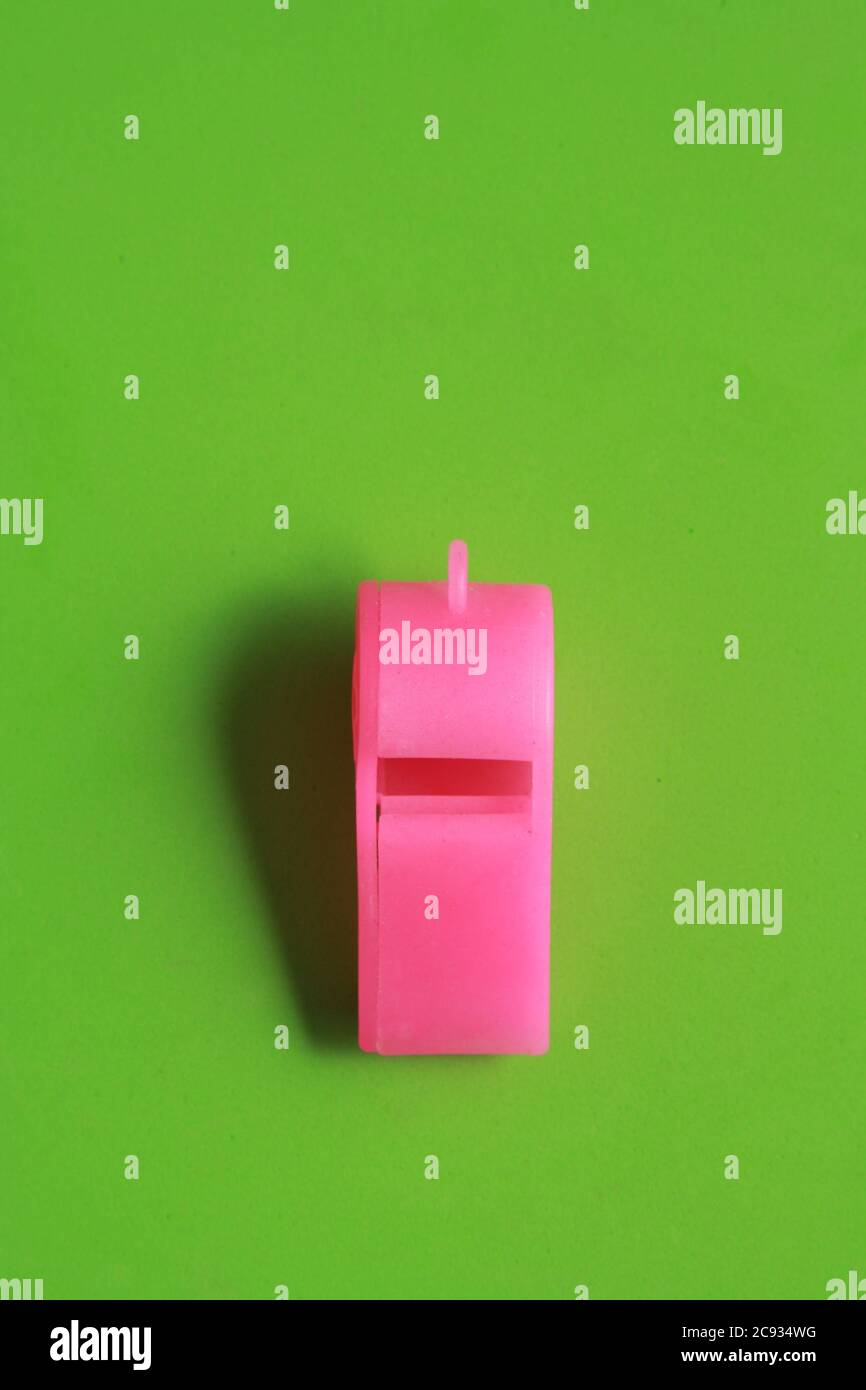 Pink plastic whistle toy isolated on a green background Stock Photo