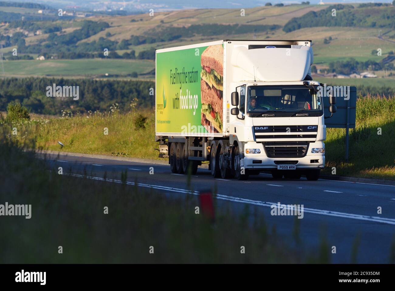DAF CF truck pulling ambient/refrigerated trailer climing to the top of Woodhead Pass on a Summer evening. Stock Photo