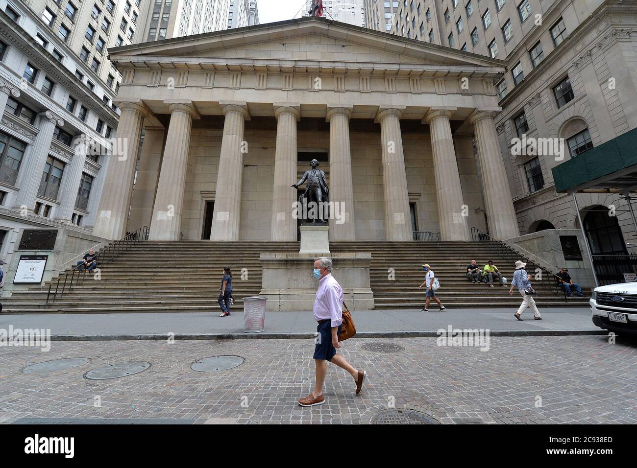 A man walks past Federal Hall and the statue of President George Washington along Wall Street, after Senate Republicans announced a $1 trillion stimulus package the day before, New York, NY, July 28, 2020. Republicans unveiled the “Heals” Act (Health, Economic Assistance Liability Protection & Schools Act), with a one time $1,200 stimulus check to every tax payer, $2,400 for married/joint filers, unemployment benefits capped at 70% of wages, Payroll Protection Program Loans and $105 billion for schools. (Anthony Behar/Sipa USA) Stock Photo