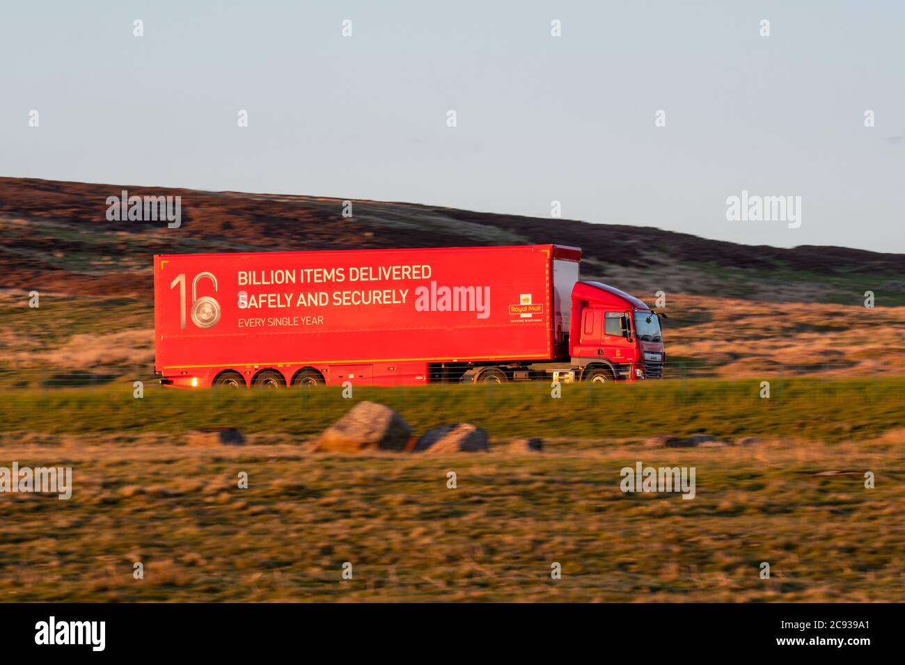 Royal Mail DAF CF truck driving along a rural motorway in Scotland with the evening sun shining on the trailer Stock Photo