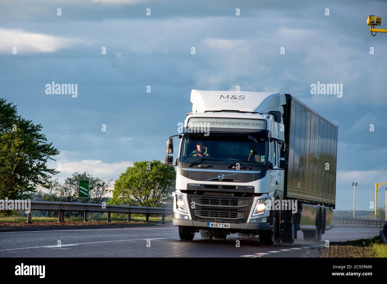 A Marks and Spencer Volvo truck pulling a curtainsider truck driving on a dual carriageway in lowland Scotland Stock Photo