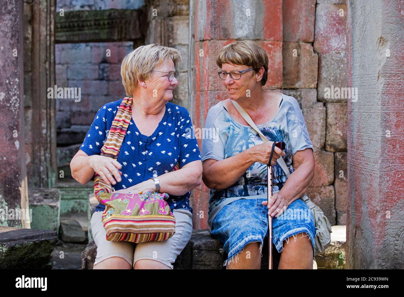 Two Western elderly female tourists resting in 12th century temple complex Angkor Wat, dedicated to the god Vishnu, Siem Reap, Cambodia, Asia Stock Photo