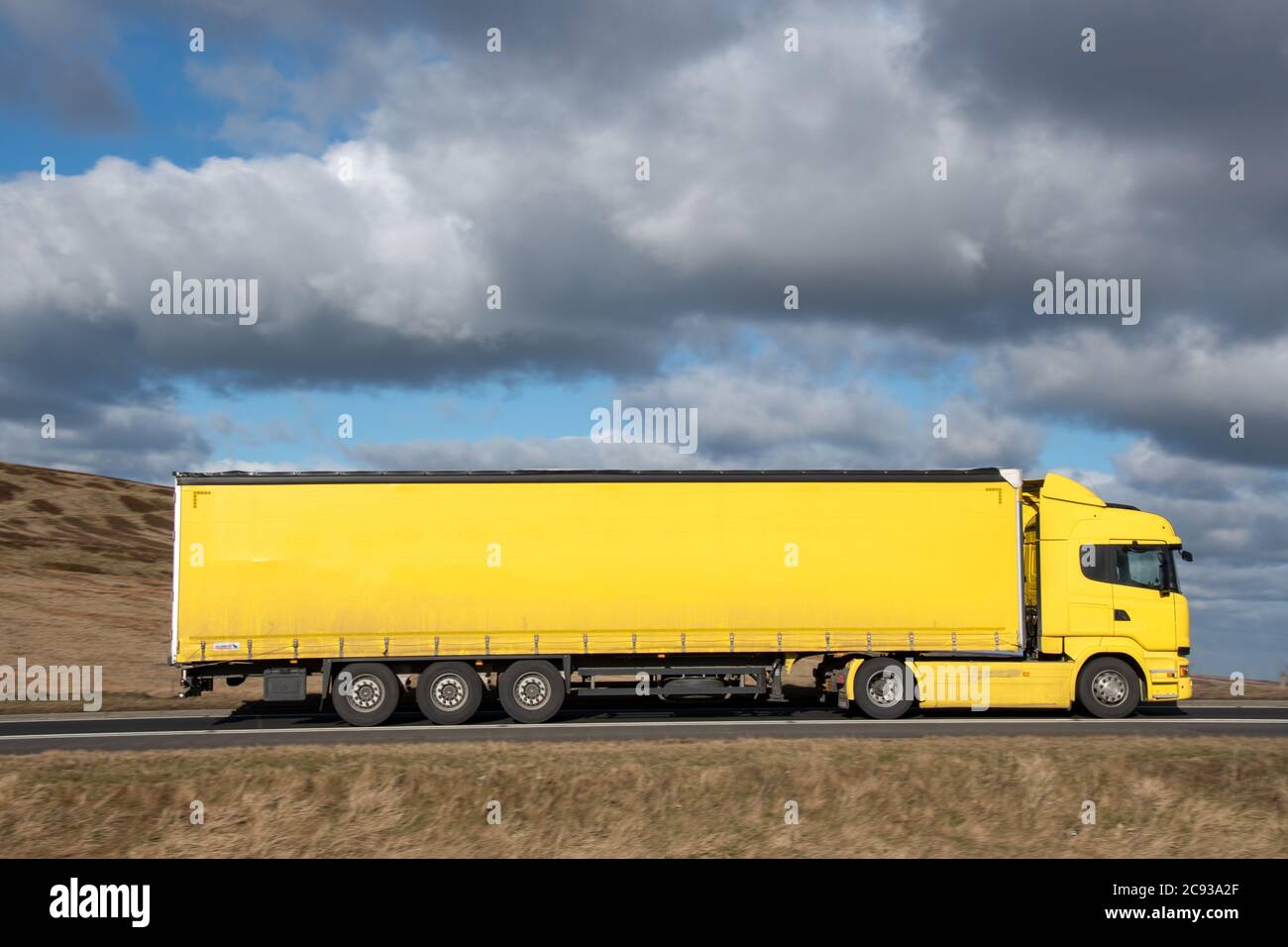 Yellow Scania truck driving on the Woodhead Pass, Yorkshire, UK Stock Photo