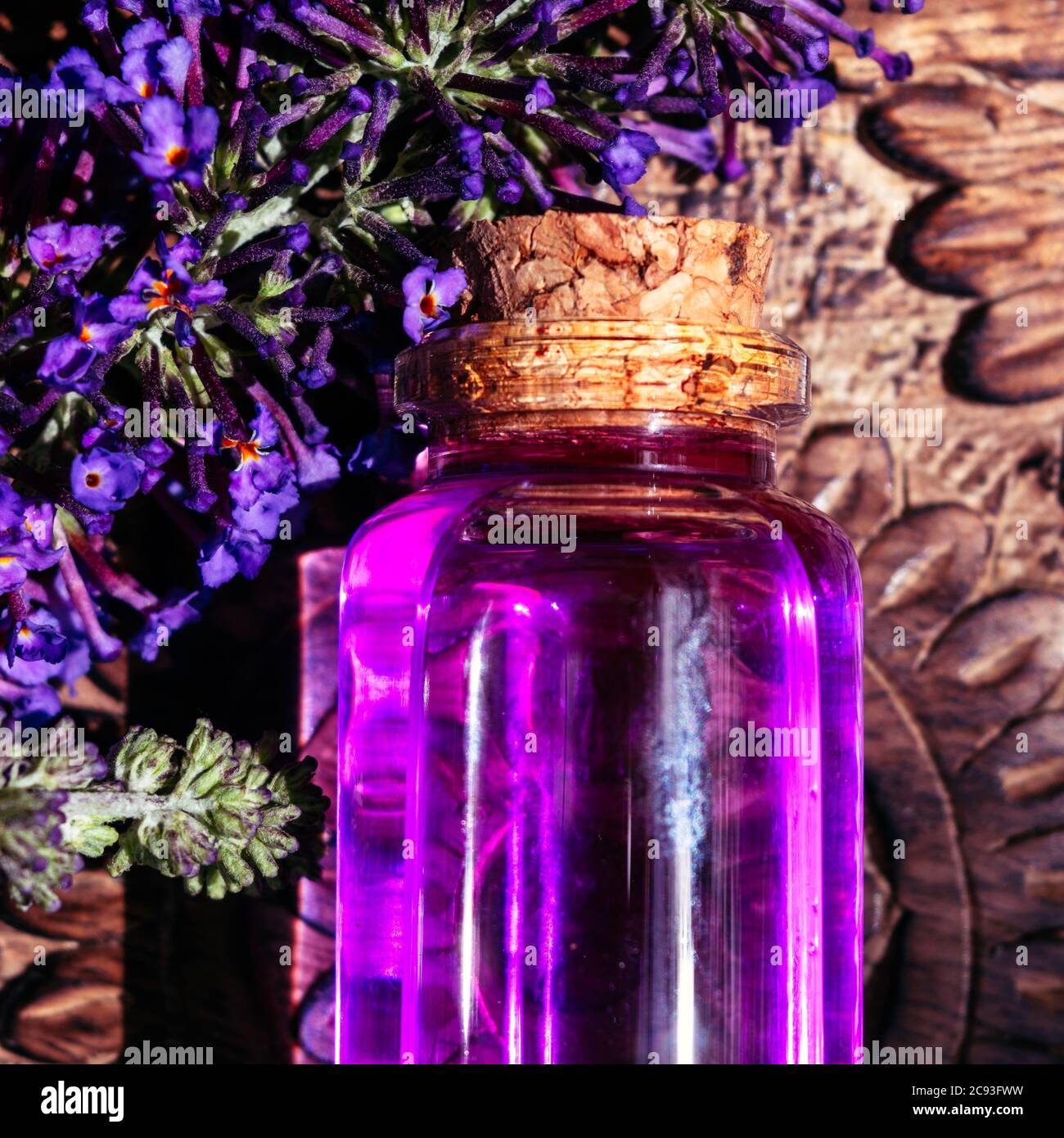 Purple potion on wooden surface with purple flowers Stock Photo - Alamy