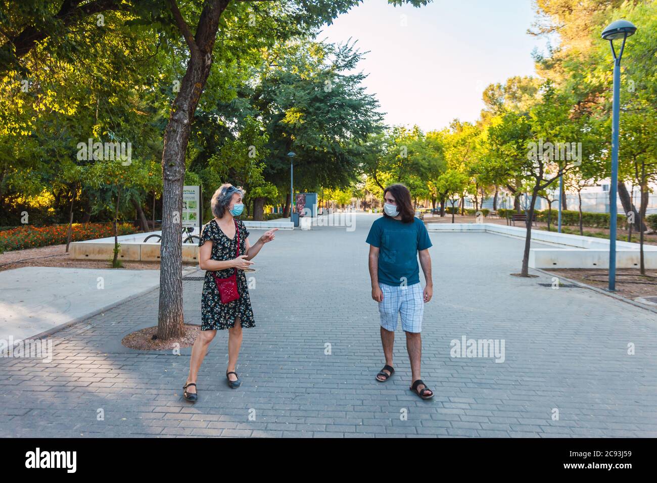 Friends wearing masks and keeping social distance in an urban park ...