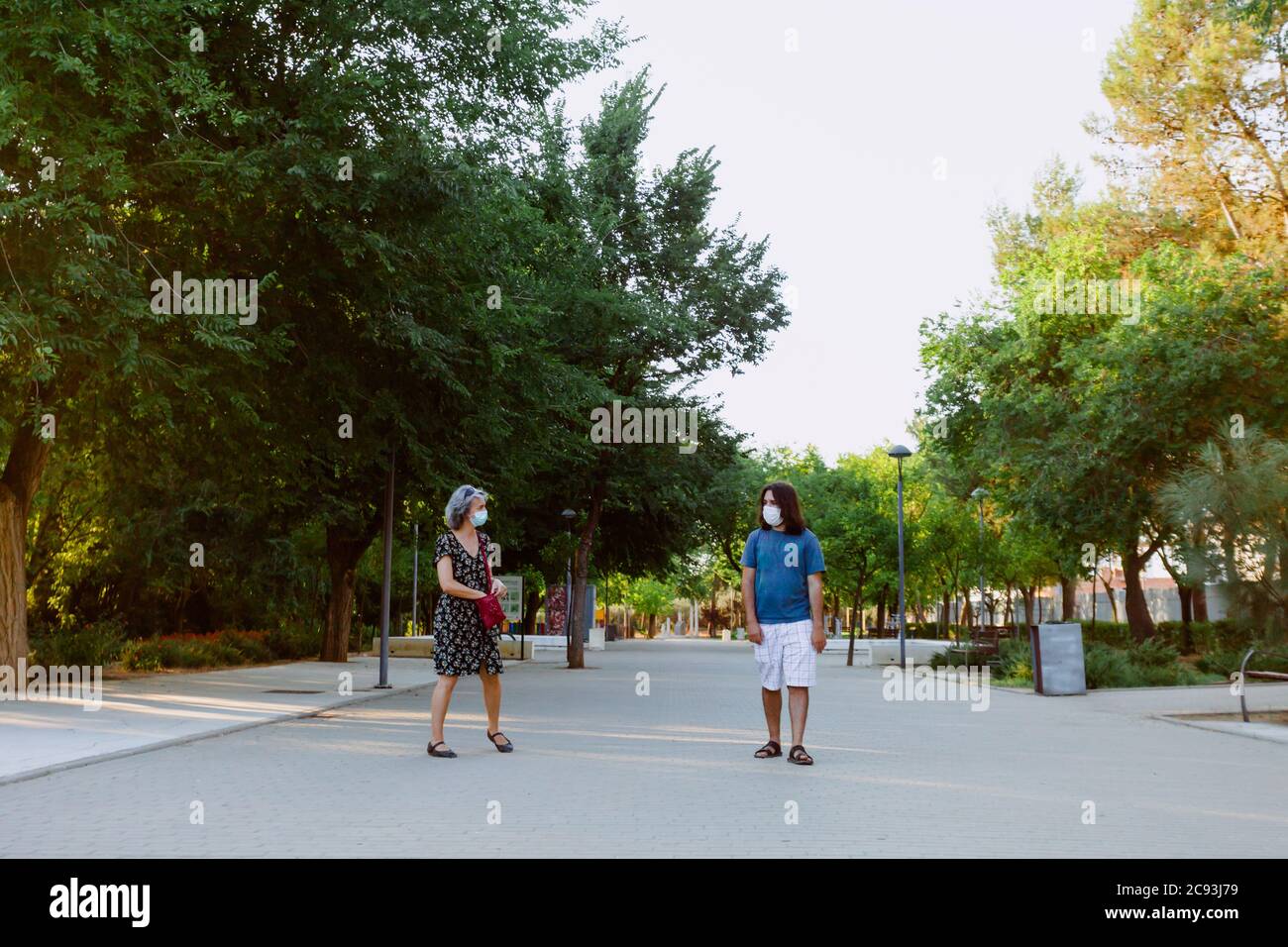 Friends wearing masks and keeping social distance in an urban park ...