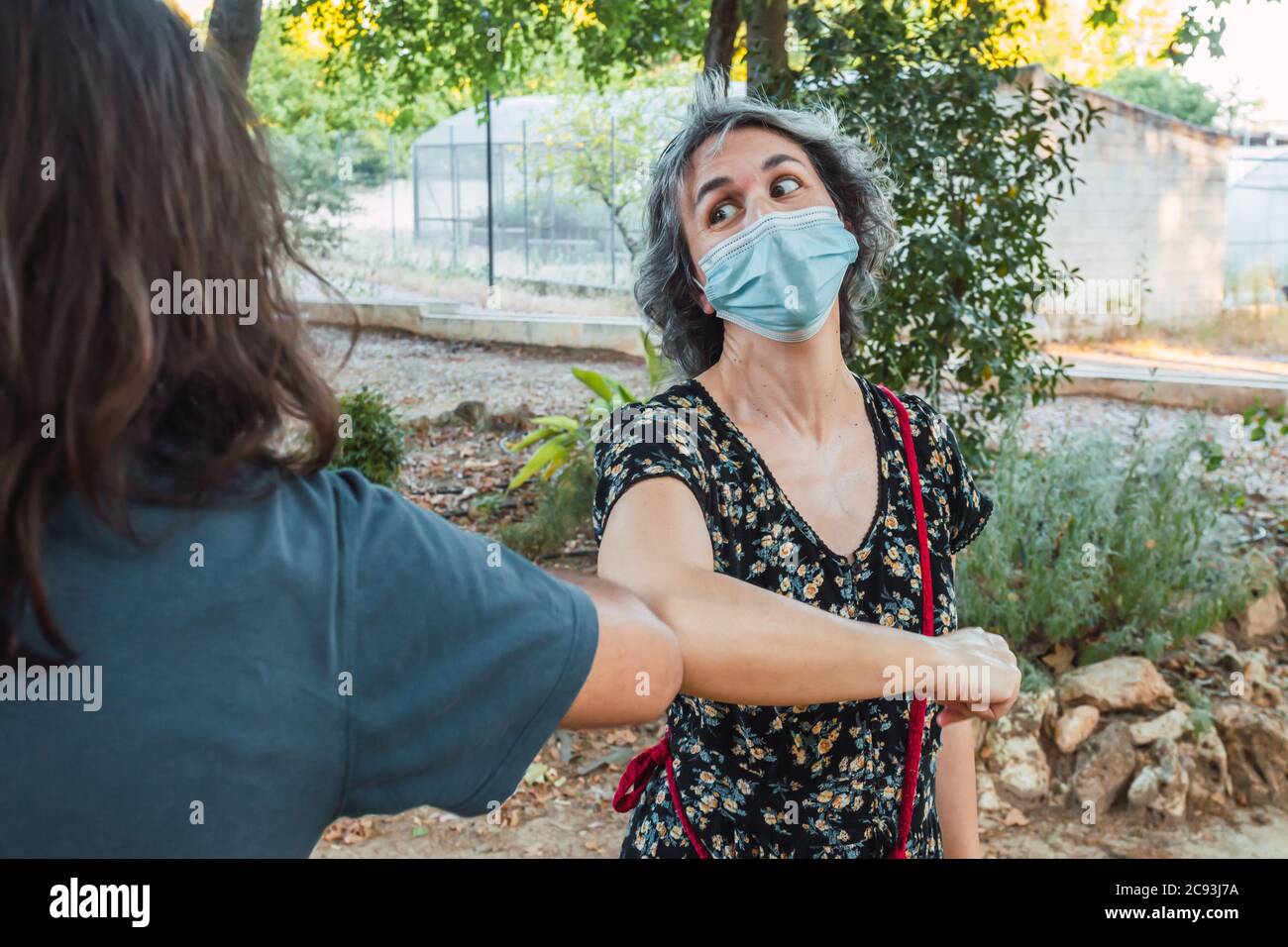 Friends wearing masks and keeping social distance in an urban park ...