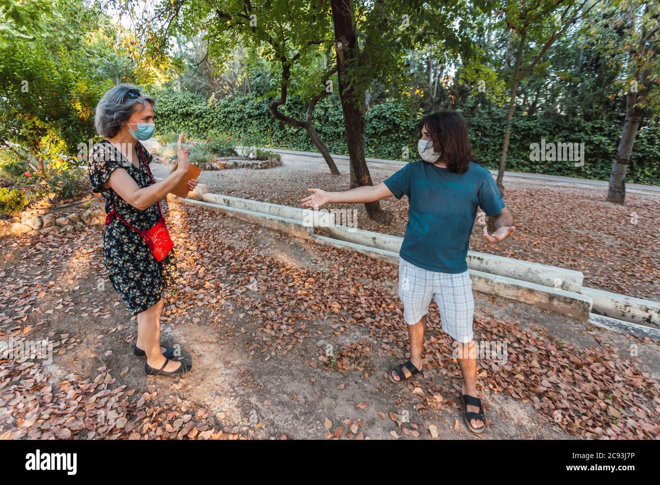 Friends wearing masks and keeping social distance in an urban park ...