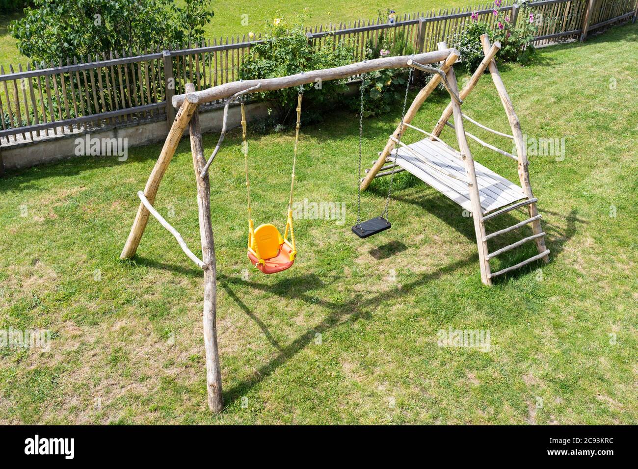 An environmentally friendly home-made wooden climbing frame and swings for children in a garden in Austria Stock Photo