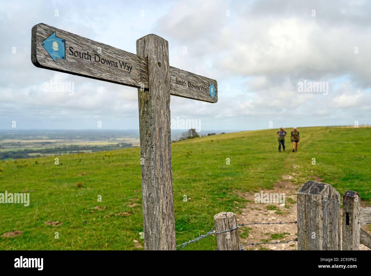 South Downs National Park, Sussex, UK near Firle Beacon. A signpost shows the route of the South Downs Way with two unrecognizable walkers. Stock Photo