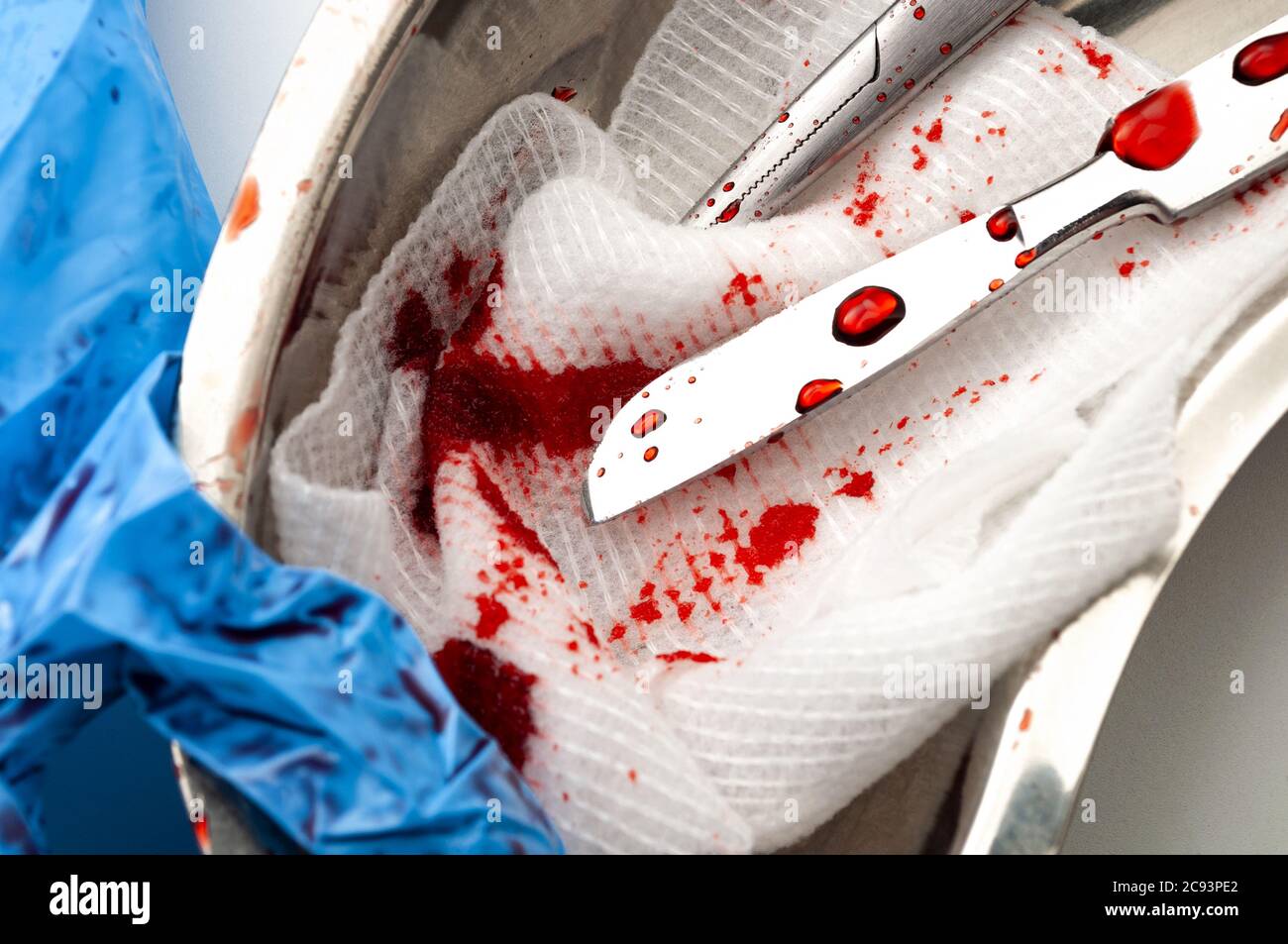 Surgery, OR instruments and dirty operating room concept theme with close up on scalpel, cotton swab, scissors and latex gloves covered in blood in a Stock Photo