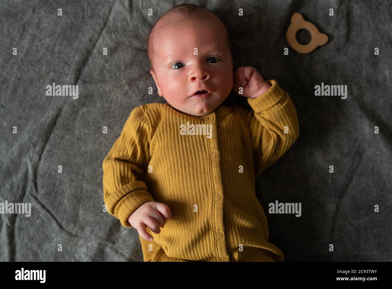 One month newborn baby with open eyes lies on his back on grey background. Close up portrait of cute little boy. Stock Photo