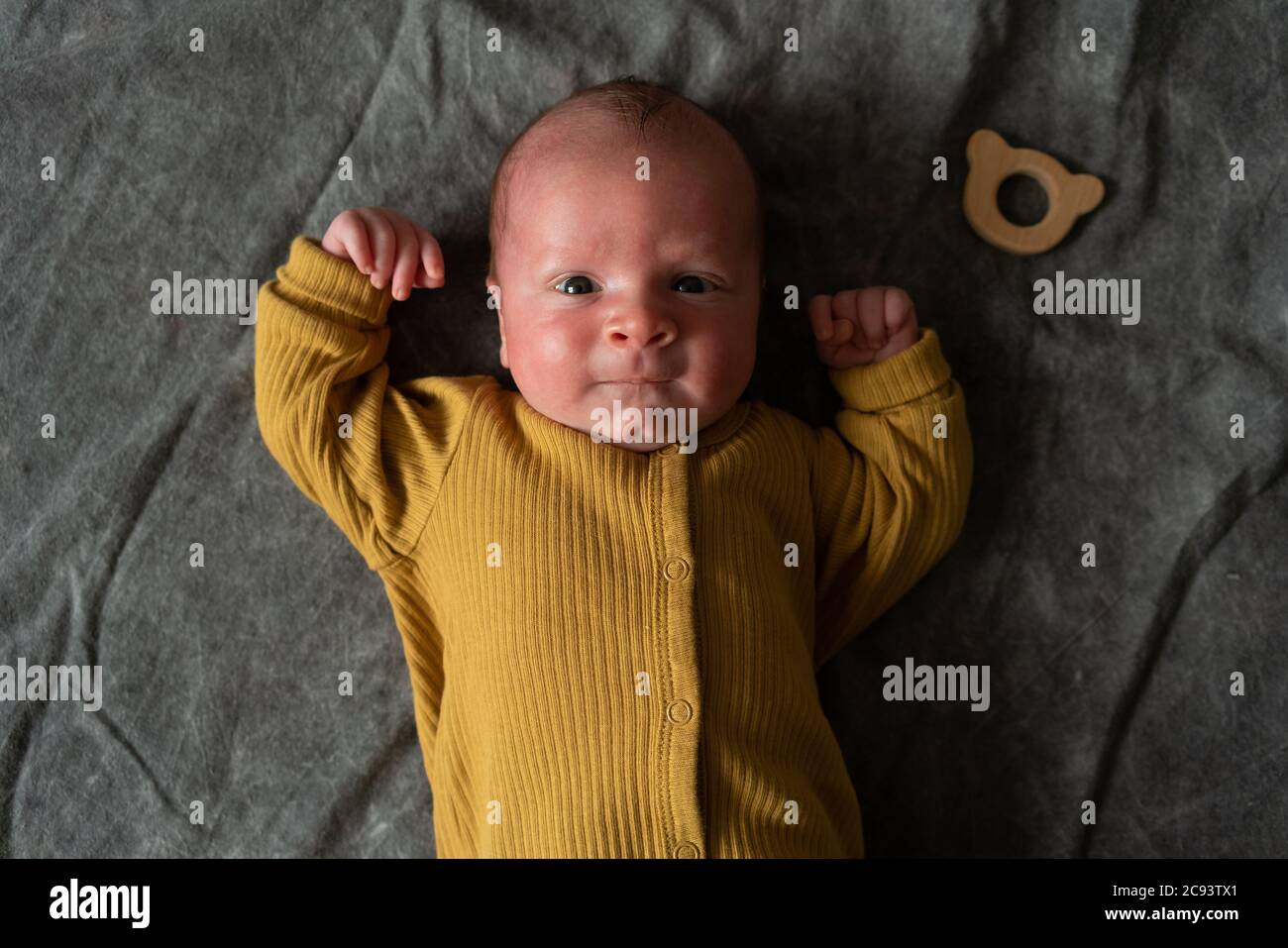 One month newborn baby with open eyes lies on his back on grey background. Close up portrait of cute little boy. Stock Photo