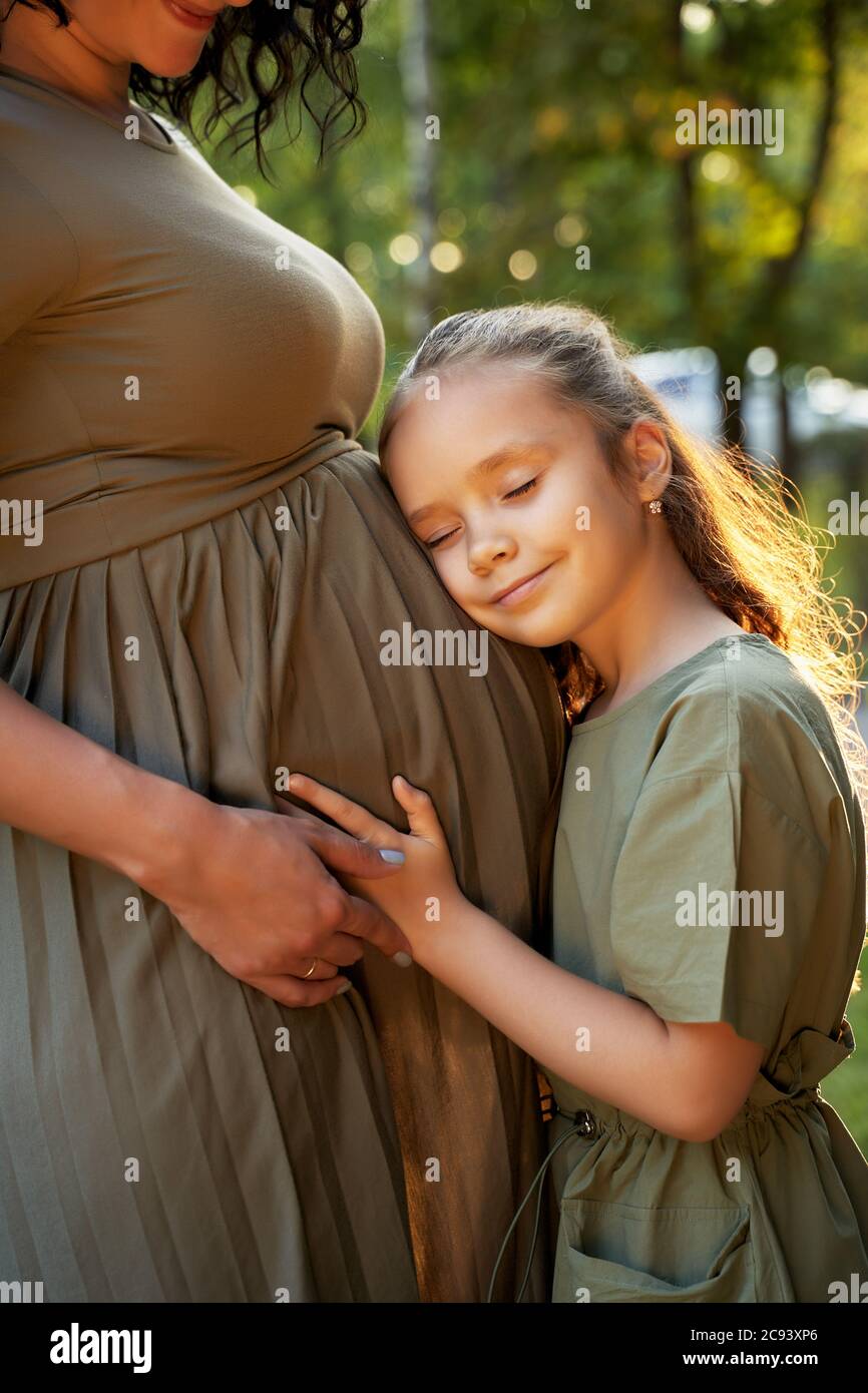 the daughter hugs the pregnant mother and waits for the appearance of her sister Stock Photo