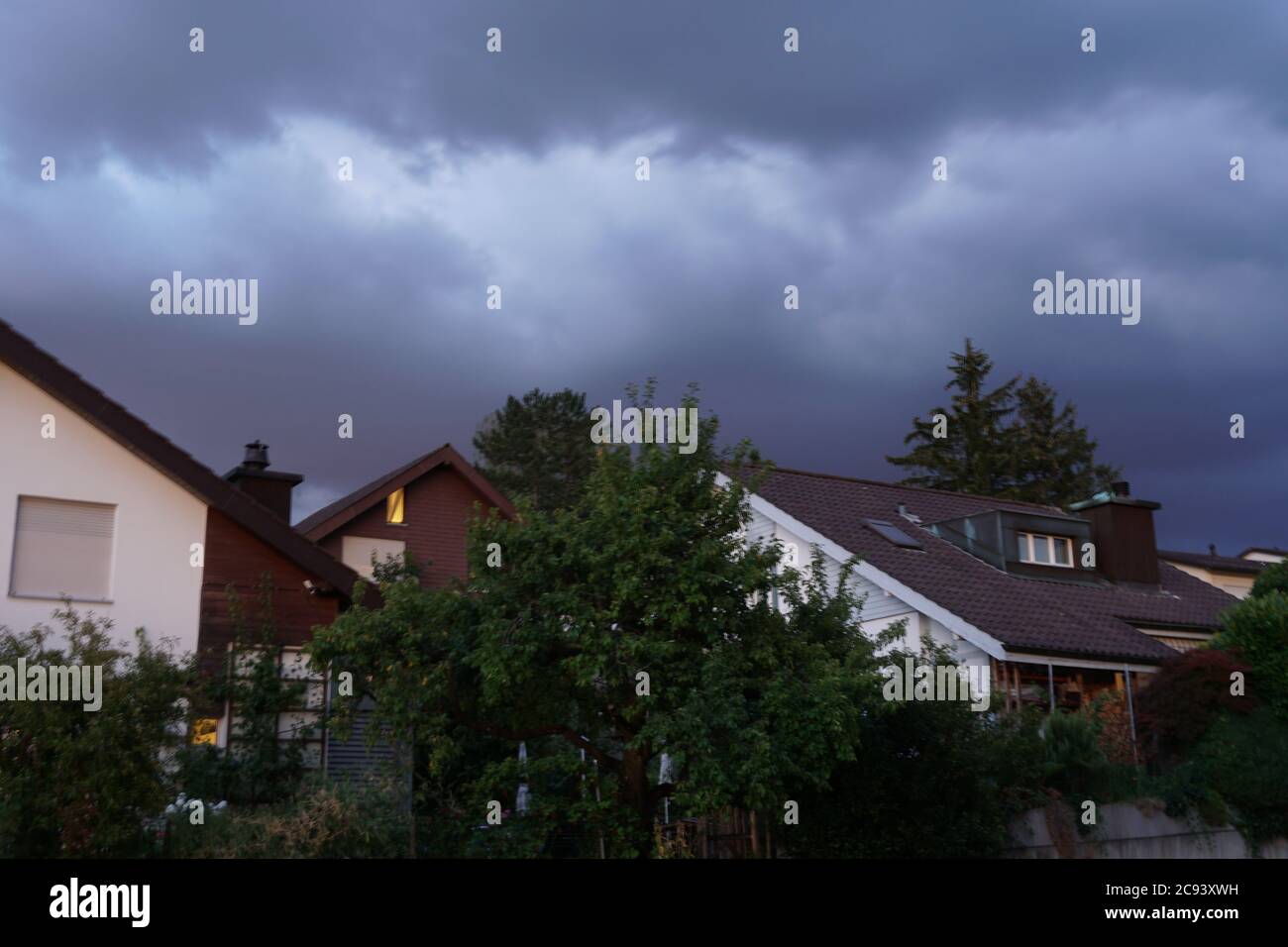 Storm heavy rainy clouds swelling above peaceful residential quarter on a summer evening in Urdorf, Switzerland. Stock Photo