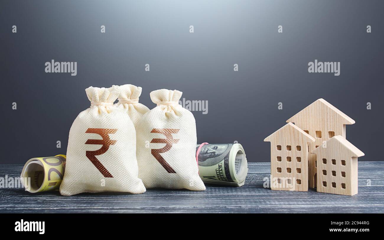Indian rupee money bags and residential buildings figures. Investments in real estate. Mortgage loan. Financing the construction and renovation of hou Stock Photo
