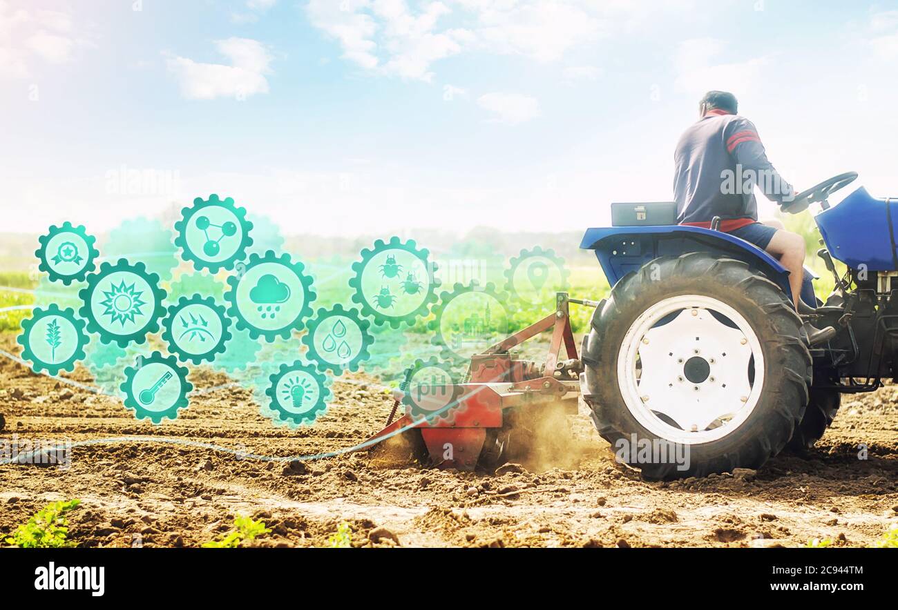 Farmer on a tractor cultivates a farm field and technological innovation gears hologram. Science of agronomy. Farming and agriculture startups. Improv Stock Photo