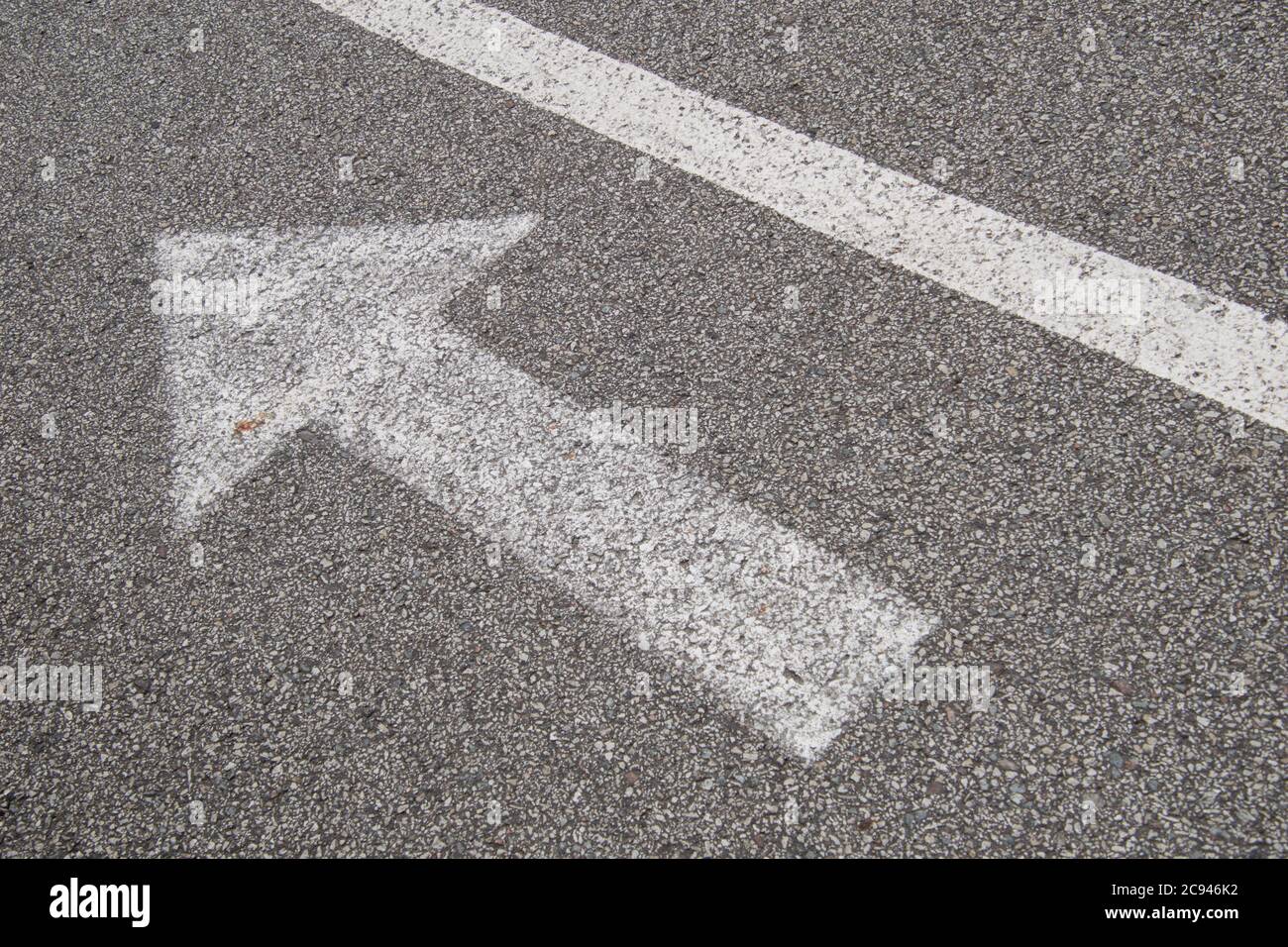 Arrow with a line, white paint on small grain asphalt. Stock Photo