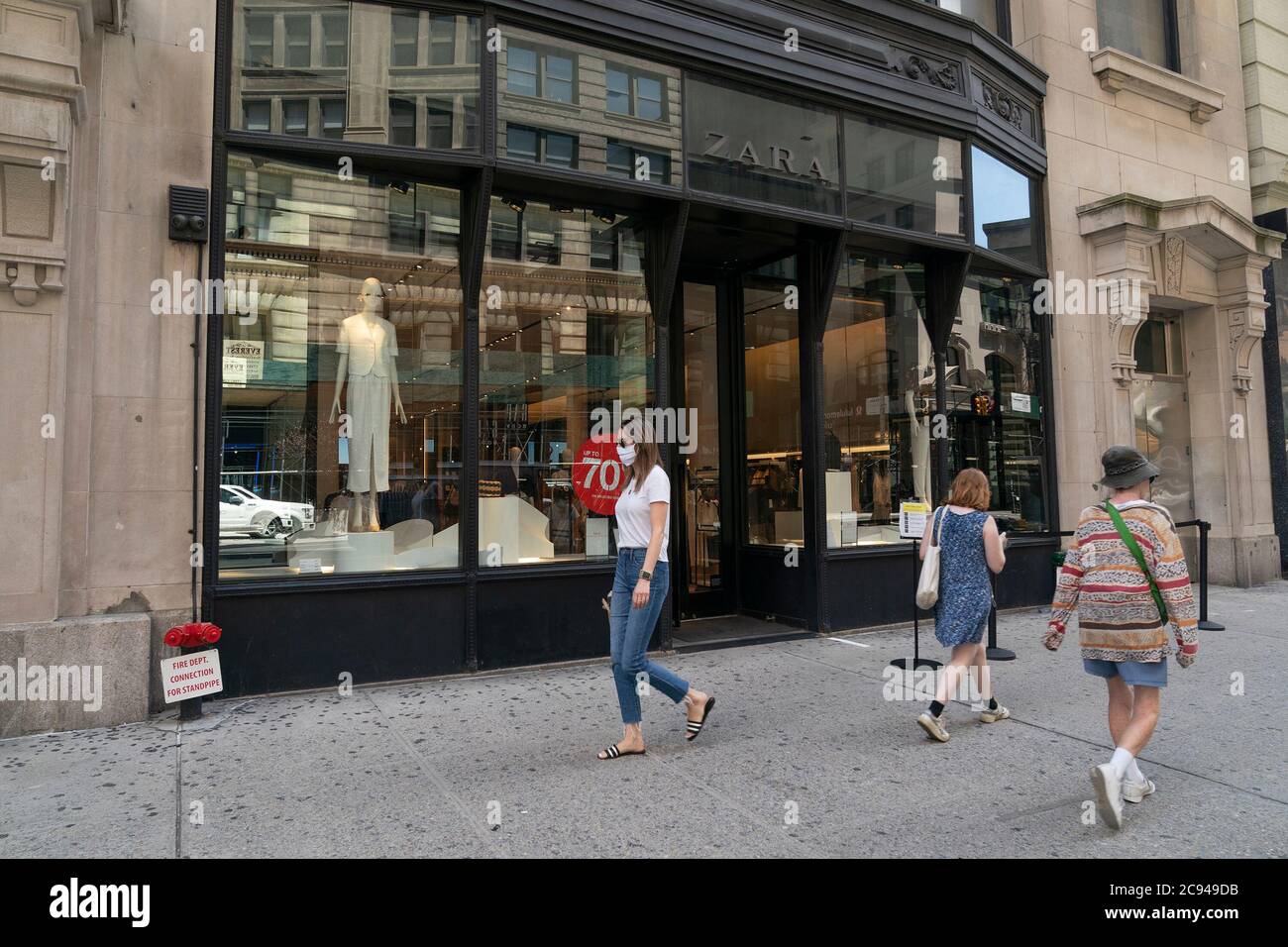 New York, United States. 28th July, 2020. Women walking by Zara store on  5th Avenue, Manhattan. Inditex, owner of brand plans to close more than  1000 stores around the world. Company announced