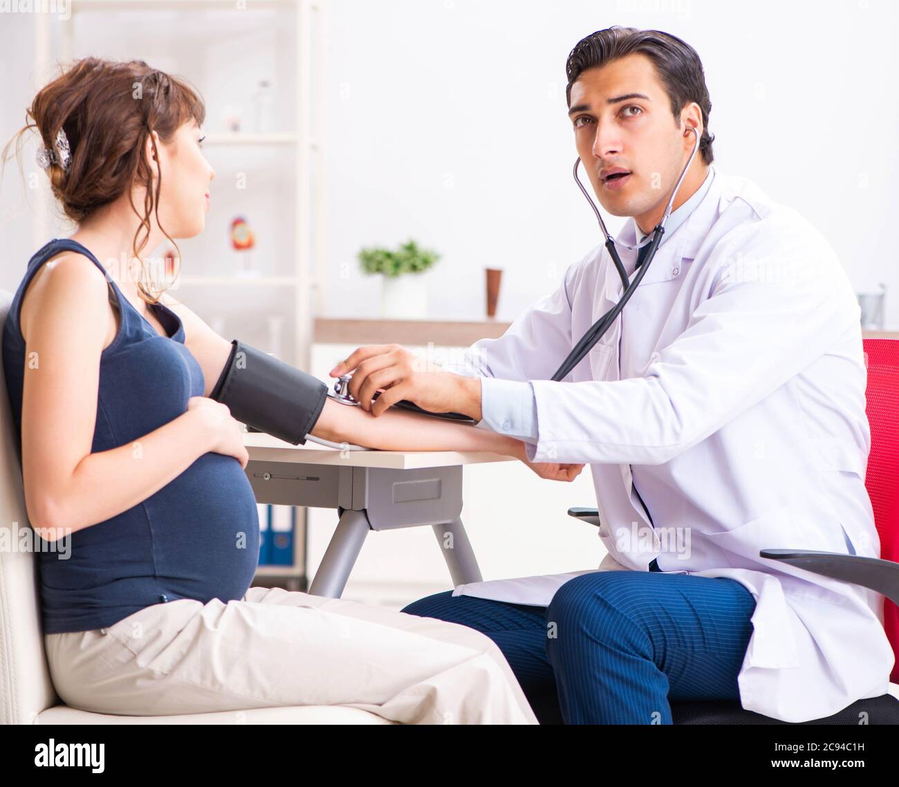 The Young Doctor Checking Pregnant Woman's Blood Pressure Stock Photo ...