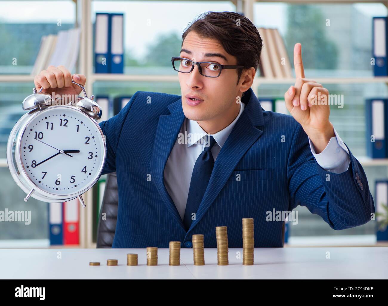 The businessman with stacks of coins in the office Stock Photo - Alamy