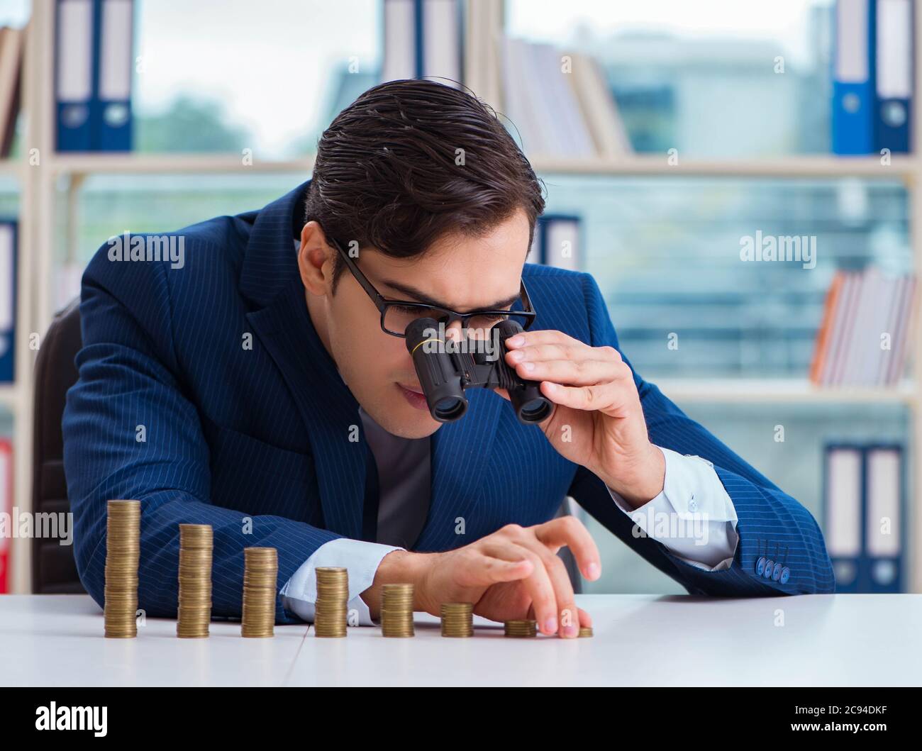 The businessman with stacks of coins in the office Stock Photo - Alamy