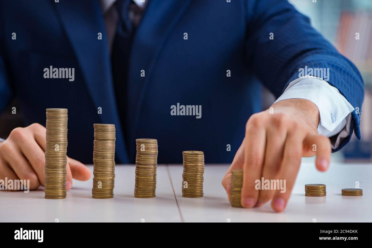 The businessman with stacks of coins in the office Stock Photo - Alamy