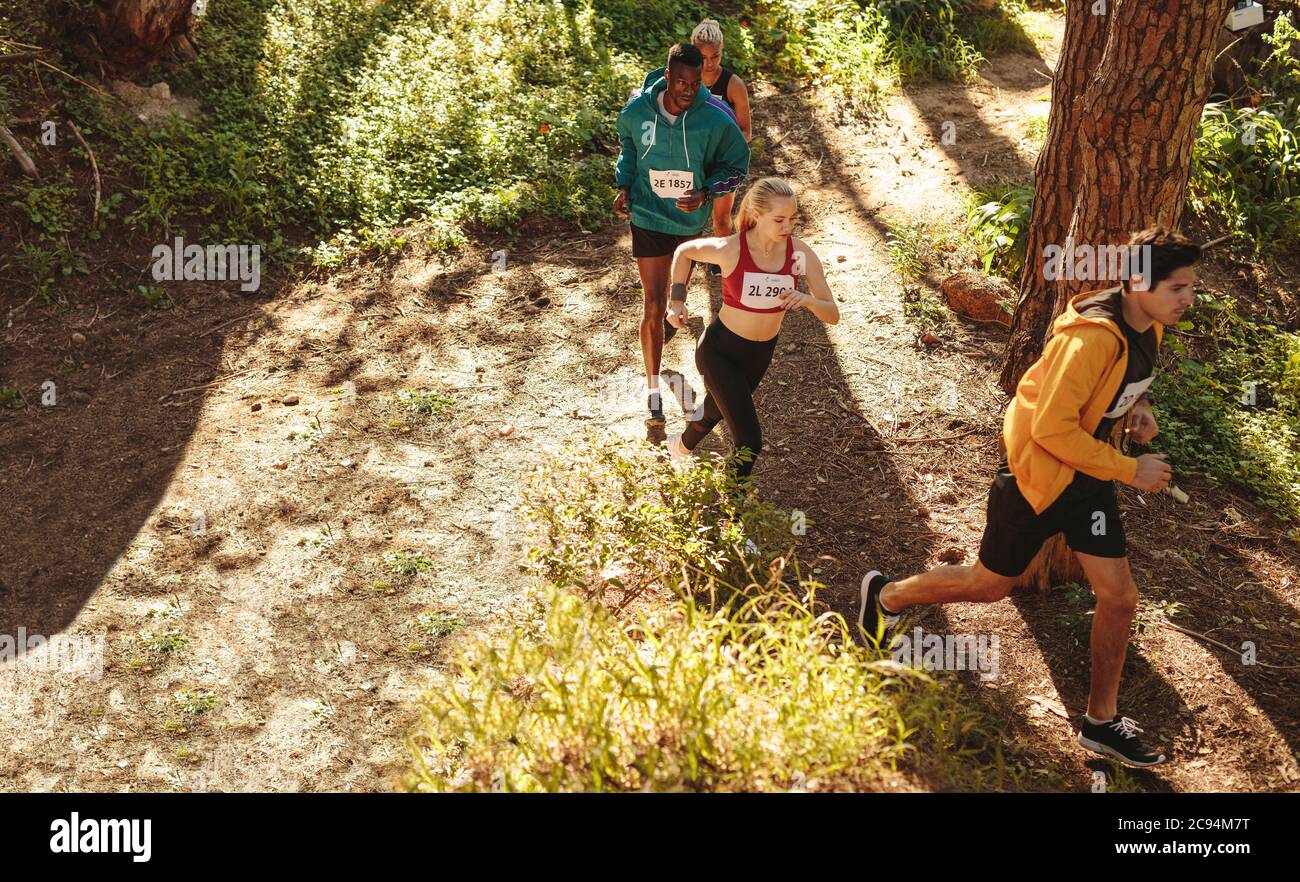 High angle view of male and female athletes people running on mountain trail. Professional athletes competing in a cross country run. Stock Photo