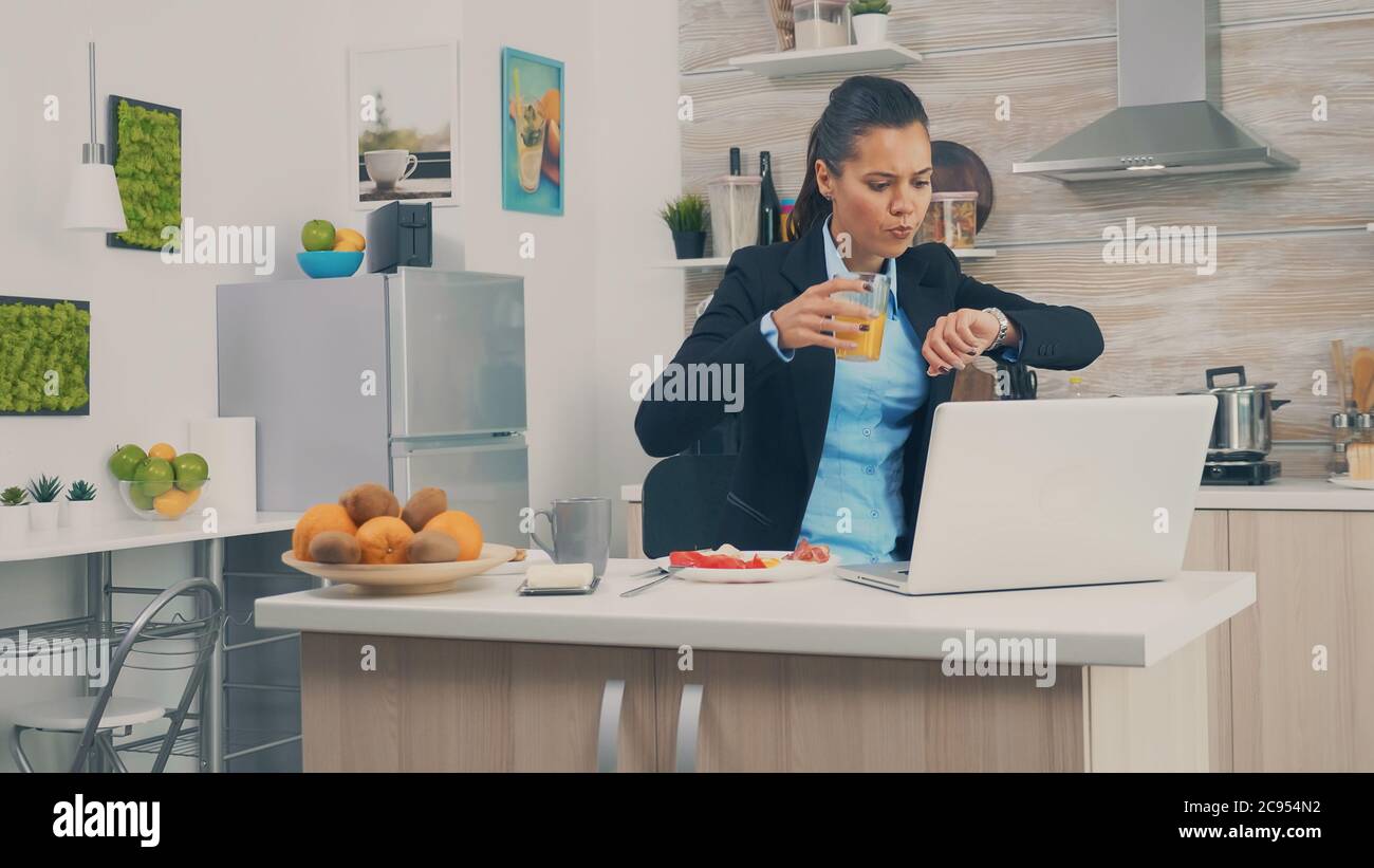 Business Woman late at the office while eating breakfast. Young freelancer working around the clock to meet her goals, stressful way of life, hurry, late for work, always on the run Stock Photo