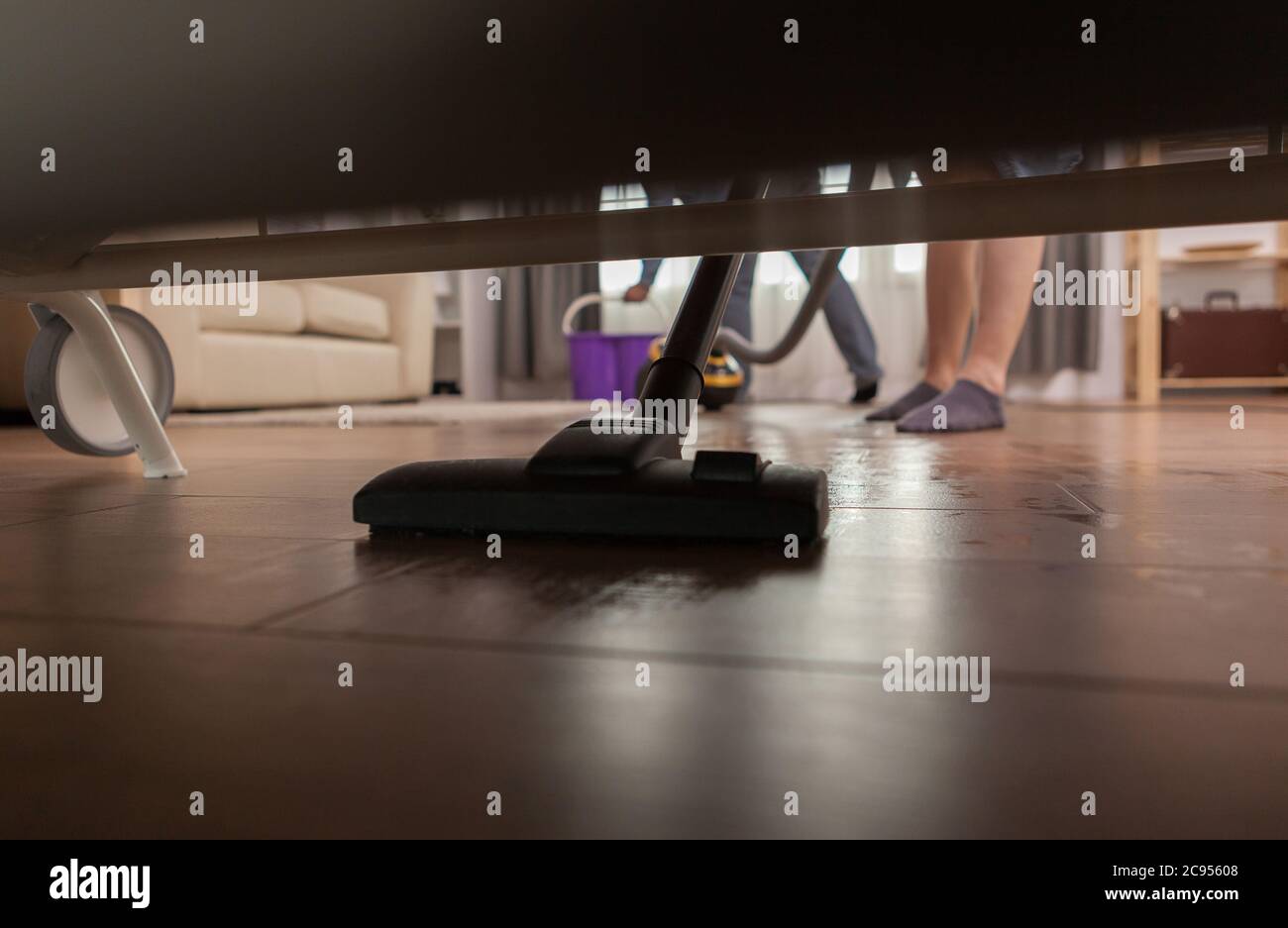 Husband cleaning dust under sofa with vacuum cleaner Stock Photo Alamy