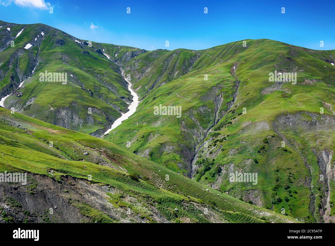 Idyllic summer landscape with hiking trail in the mountains with beautiful fresh green mountain pastures, blue sky and clouds. Tian-Shan, Kyrgyzstan. Stock Photo