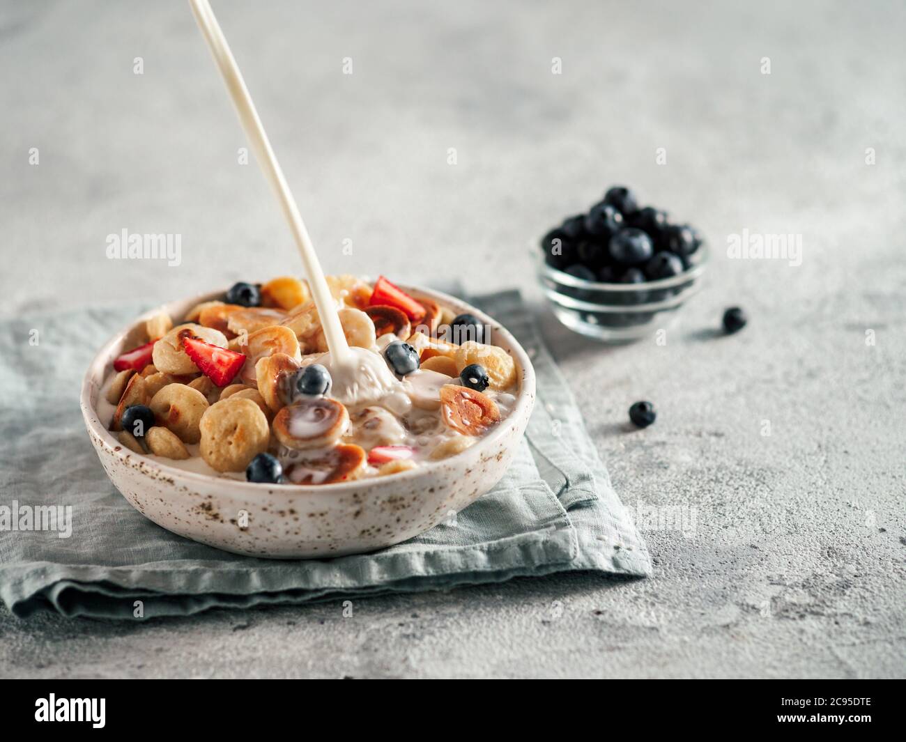 Trendy food pancake cereal. Milk pouring on heap of mini cereal