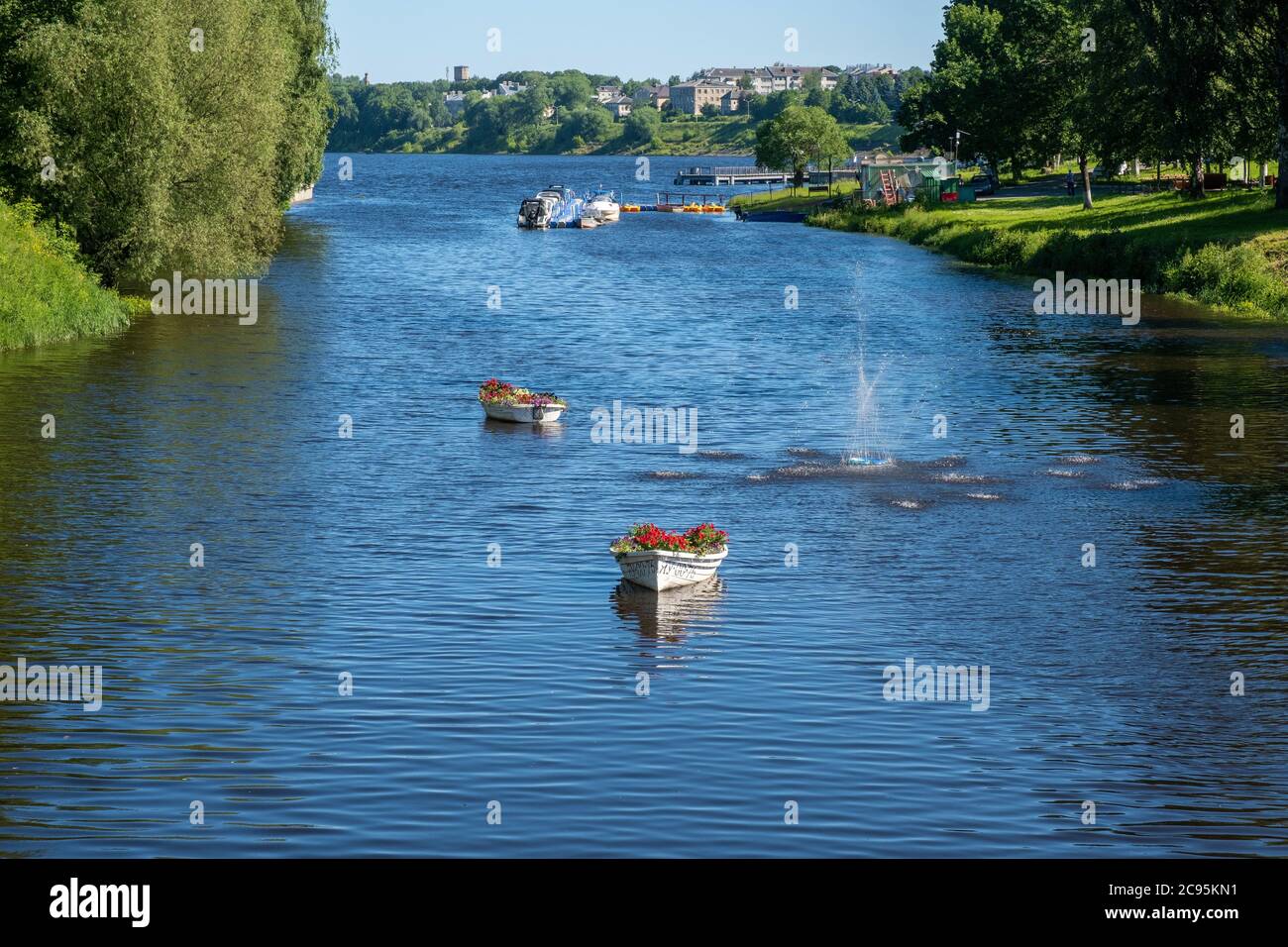 A fountain and two white boats with flowers in the Kamenny brook flowing into the Volga river on a sunny summer day. Stock Photo