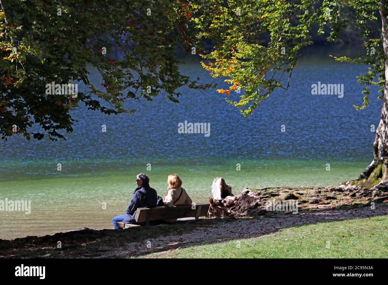 Aged couple enjoy spring morning on the bench near lake in the park Stock Photo