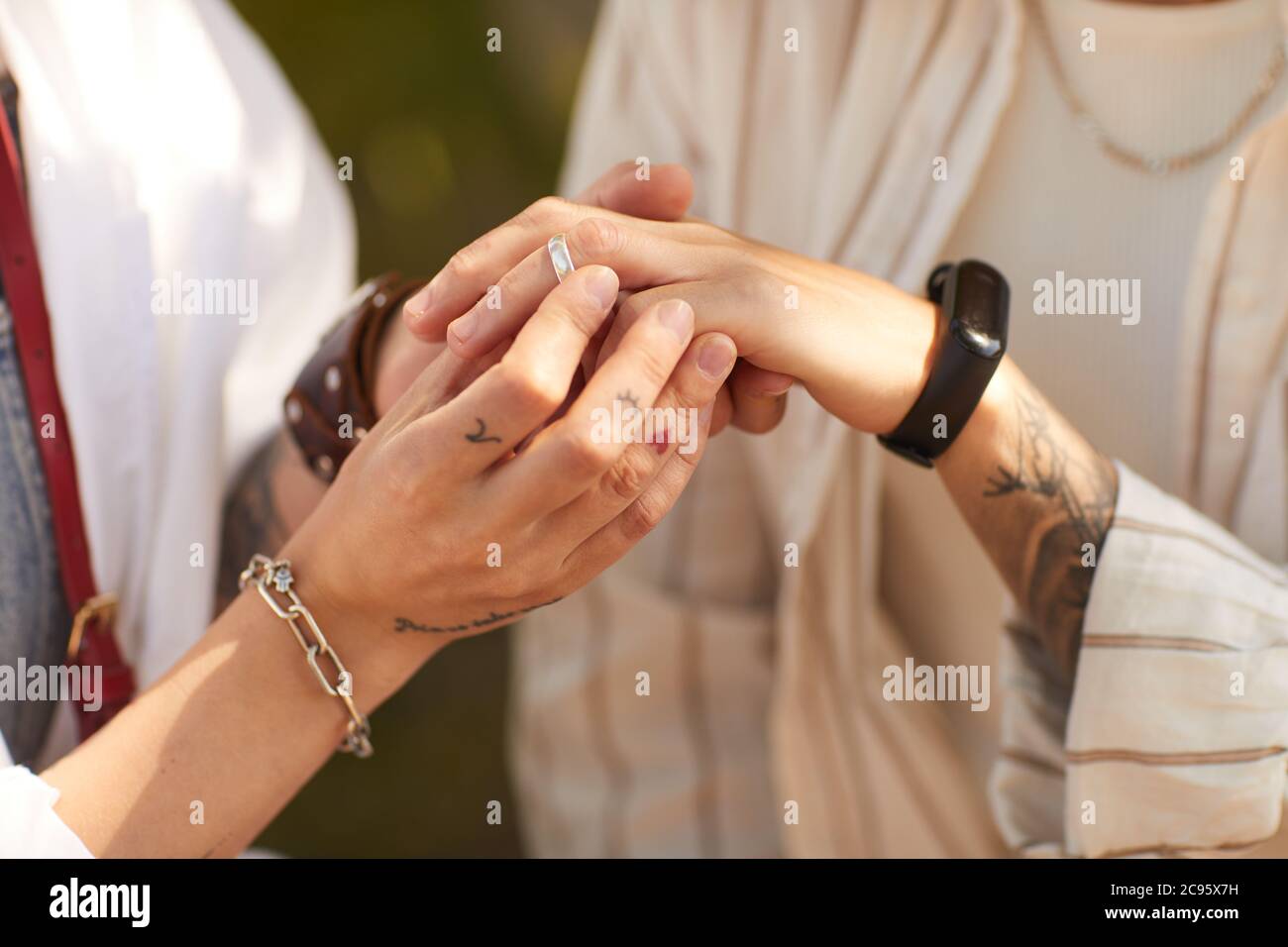 Closeup of woman putting ring on her girlfriend's finger they are