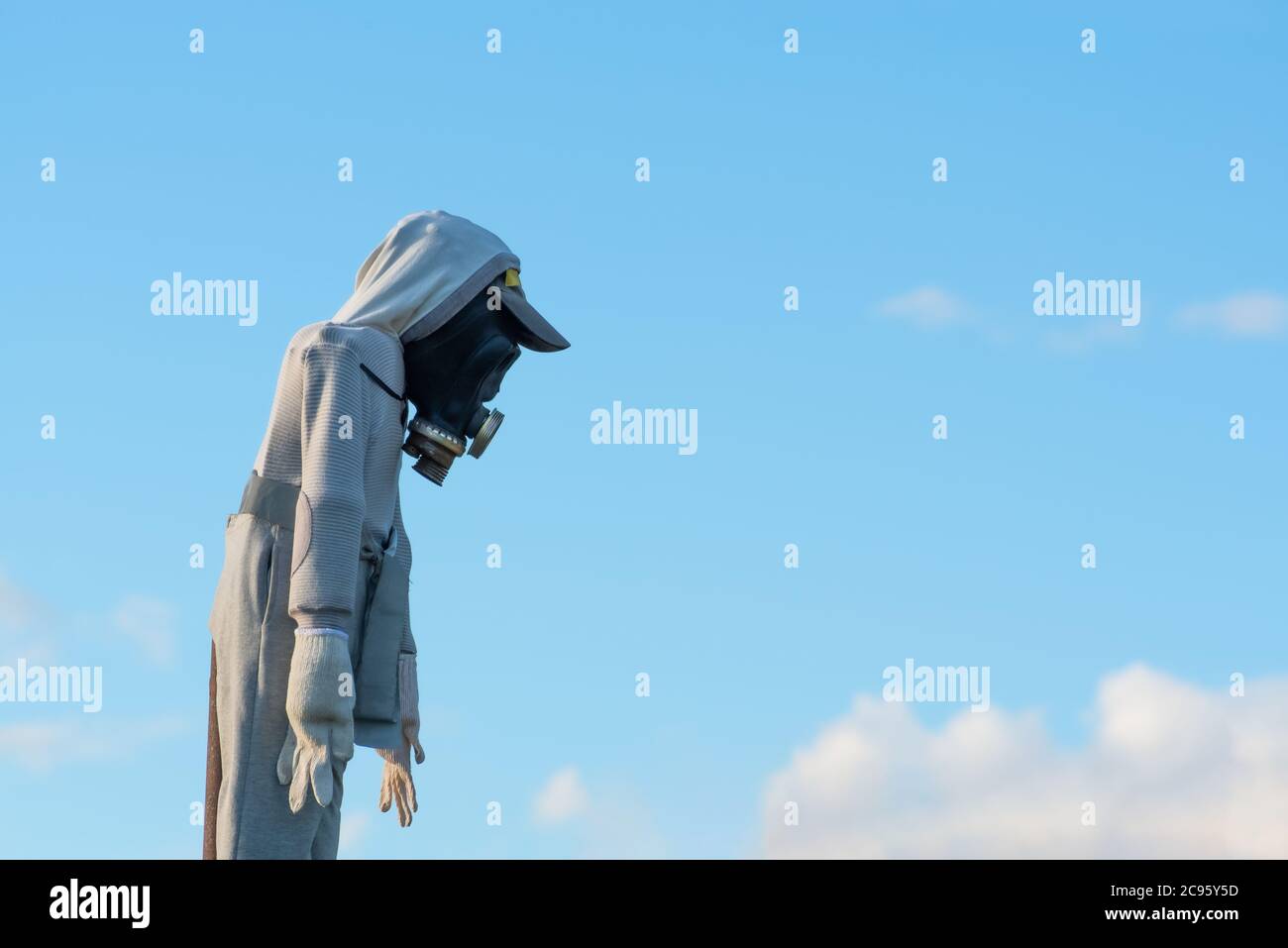 mannequin, scarecrow with gas mask against blue sky, symbolizing air pollution problem, global spread of the virus on the planet, chemical catastrofe Stock Photo