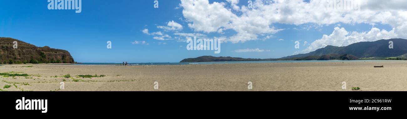 Panorama of new caledonia beach at Poe on a sunny day. Sky is blue with white clouds. Turtle bay on the right side. Panoramic seascape Stock Photo