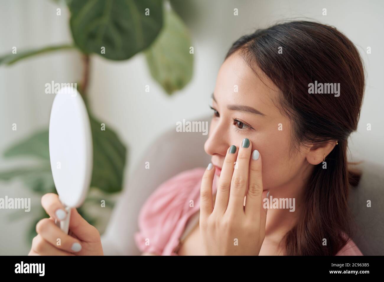 Beautiful face young Asian woman looking at the mirror, with cosmetic treatment, healthy concept. Stock Photo