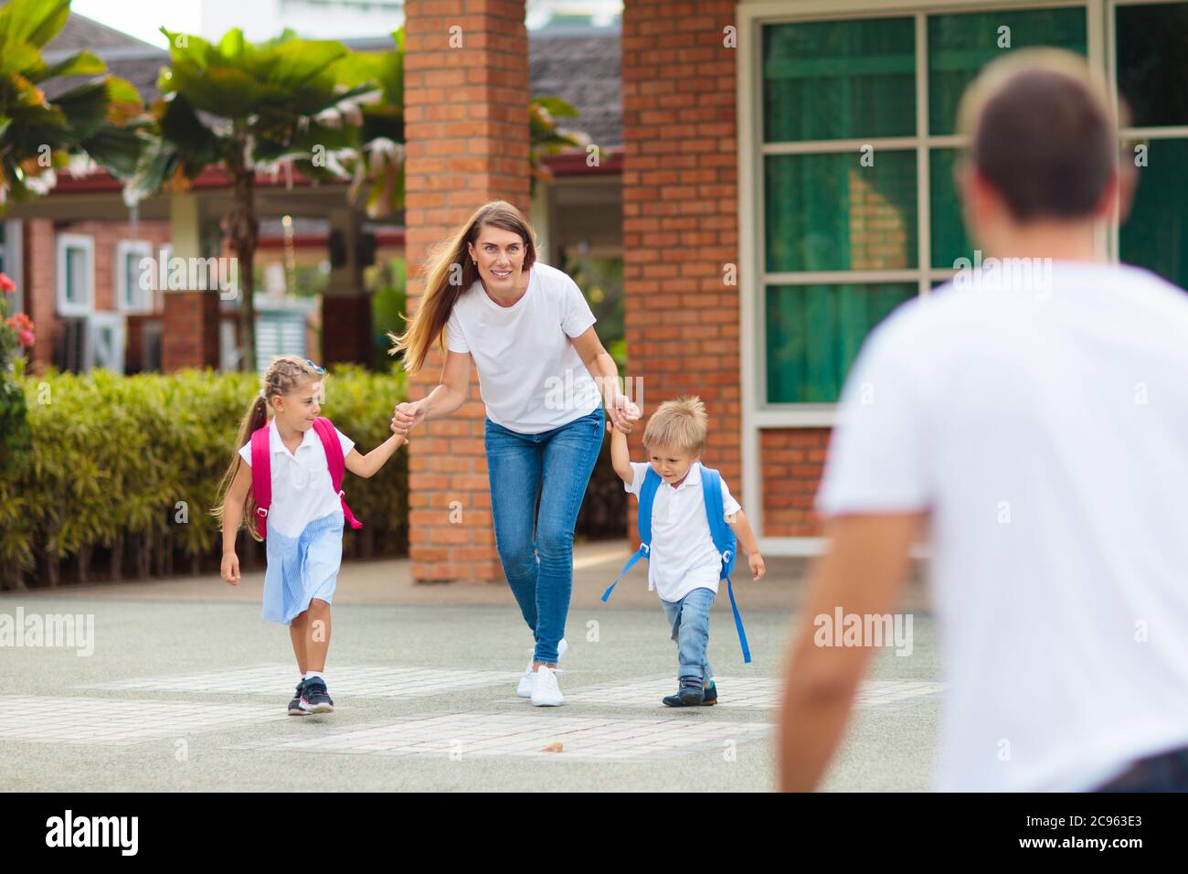 Mother and kids after school. Young mom picking up children after