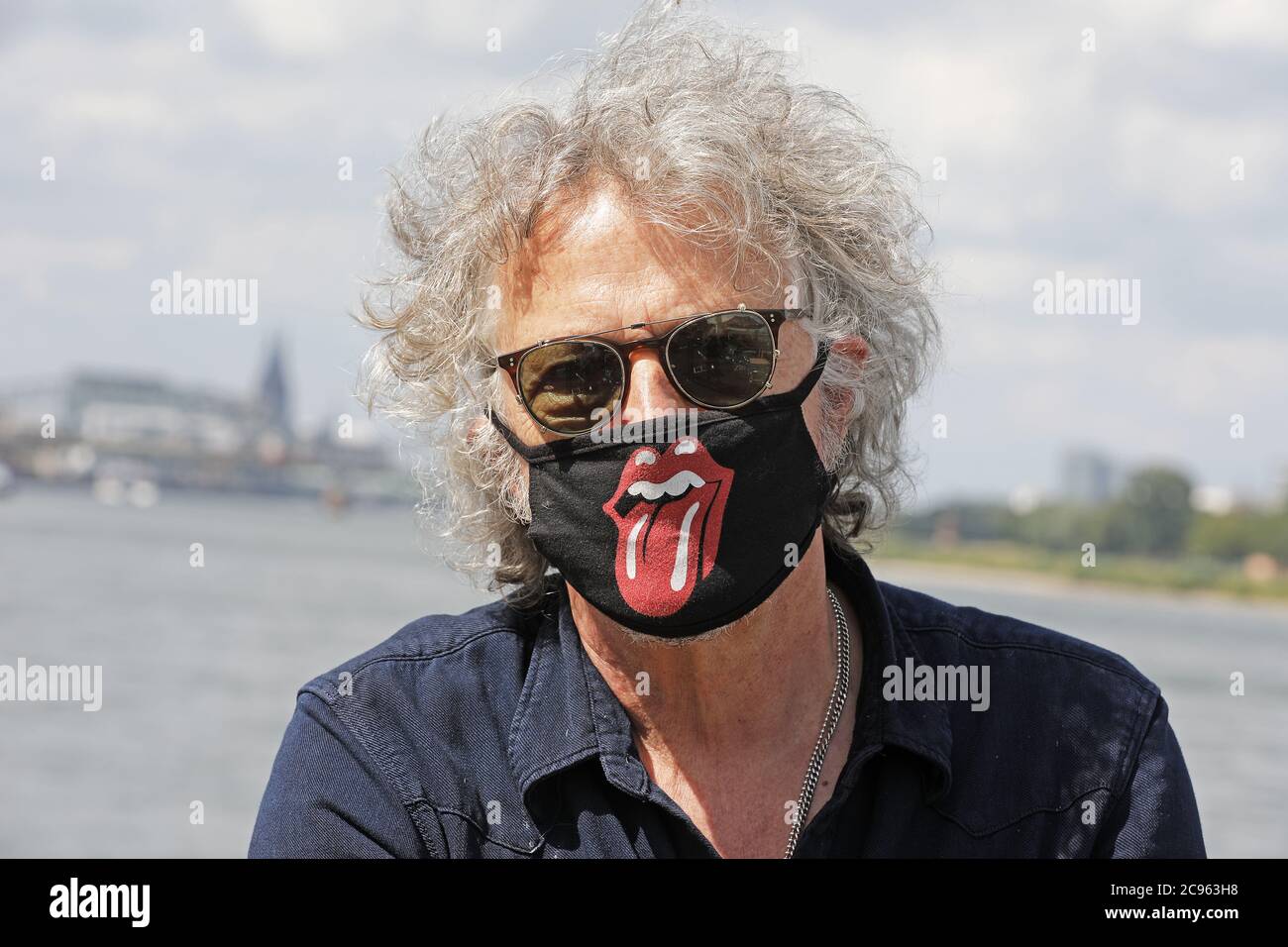 Cologne, Germany. 28th July, 2020. The musician and singer Wolfgang Niedecken stands on the Rhine with a mouthguard bearing the tongue logo of the Rolling Stones. (To dpa: 'Freedom in Corona times: Taken early, melted away fast?') Credit: Oliver Berg/dpa/Alamy Live News Stock Photo