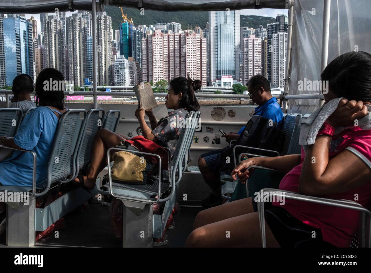 Passengers on a ferry wear surgical masks during a trip between Lamma Island and the Central district of Hong Kong. Summer 2020 is marked by the scenes related to the coronavirus pandemic. Surgical masks and warnings banning people from accessing the scenario. Stock Photo