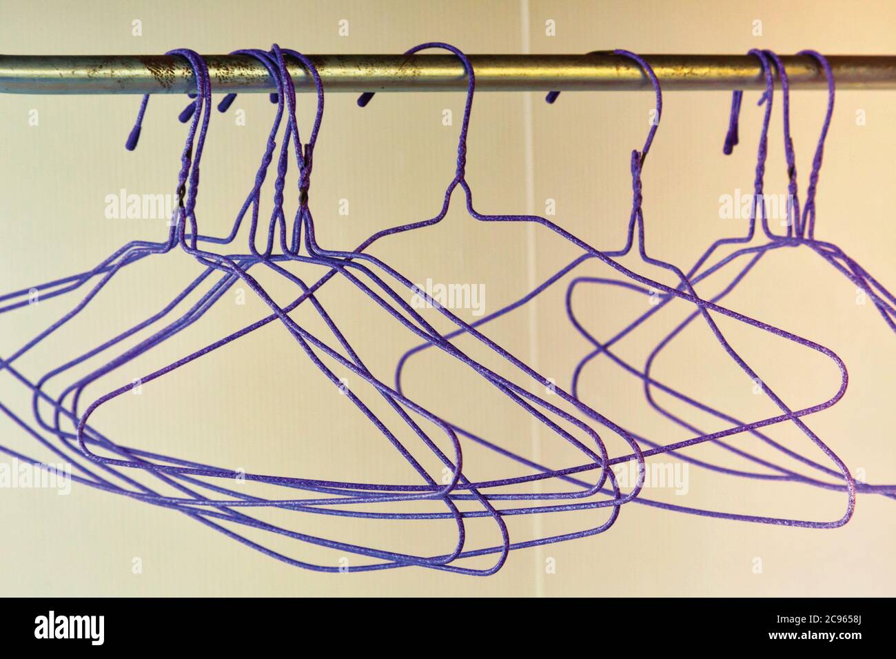 https://c8.alamy.com/comp/2C9658J/group-of-empty-purple-wire-coat-hangers-hanging-on-rail-2C9658J.jpg