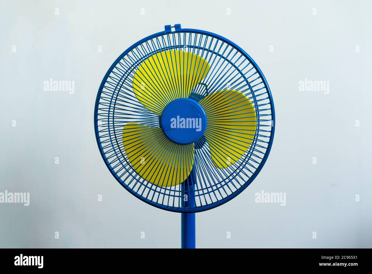 A colorful blue and yellow standing fan for cool air in a hot summer Stock Photo