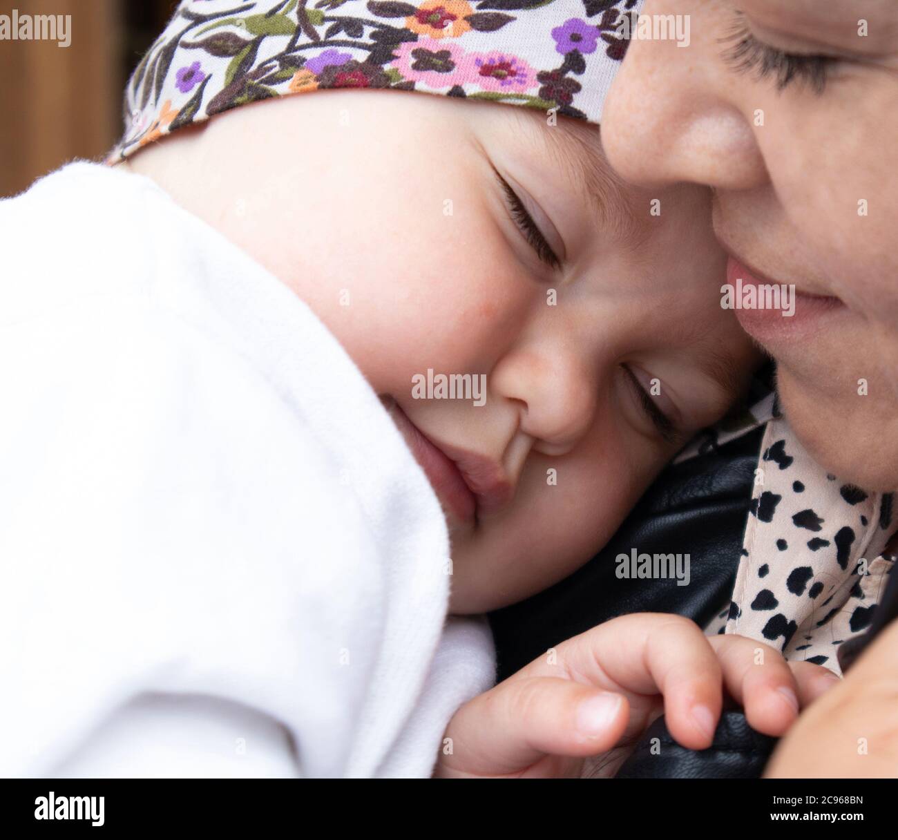 Little cute baby girl sleeping on the shoulder of her mother, tender