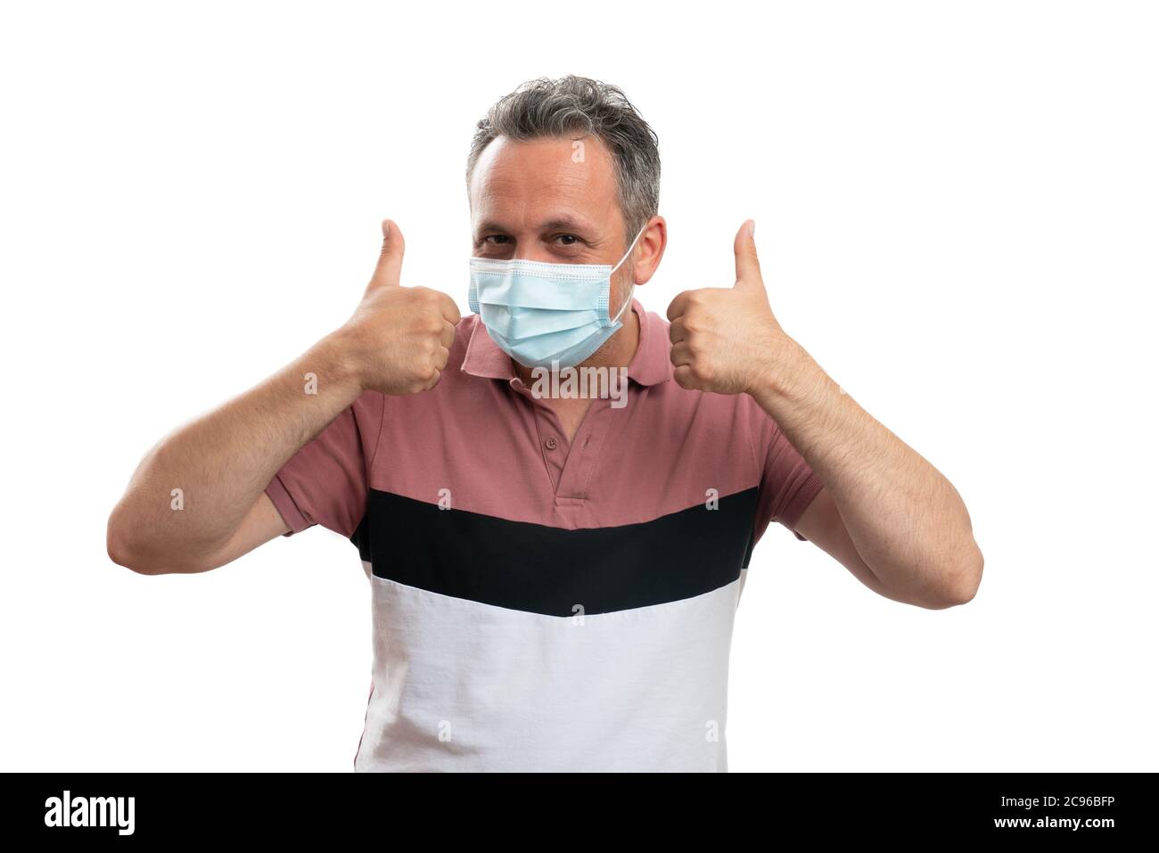 Guy wearing a medical disposable mask showing thumbs-up as good prevention against influenza pandemic and healtchare concept Stock Photo