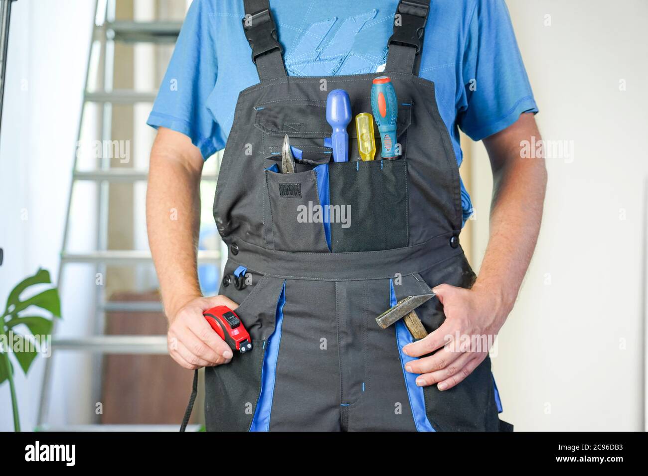 worker in overalls with tools stands against the background of repair Stock Photo