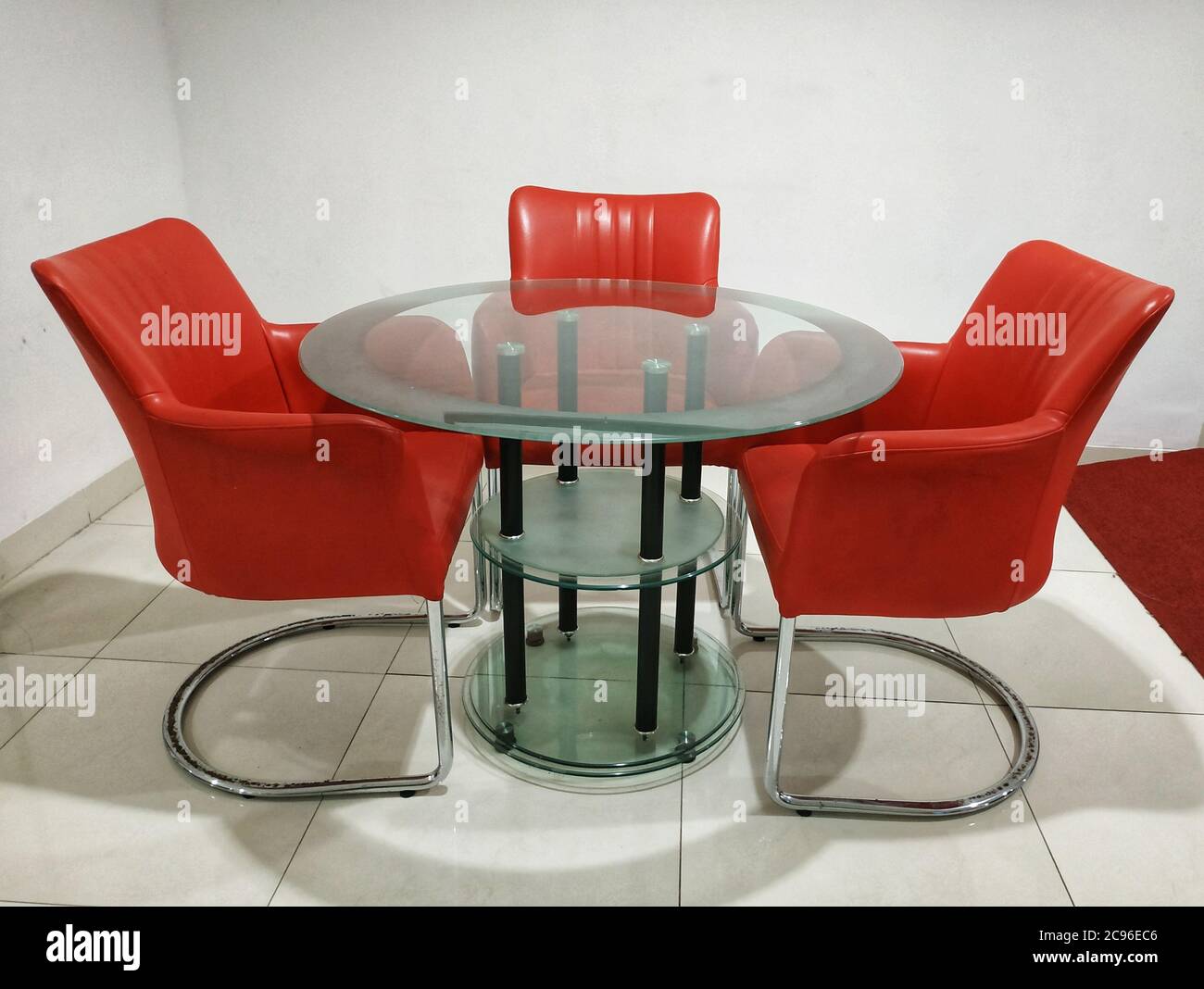 Round glass table with red chairs Stock Photo Alamy